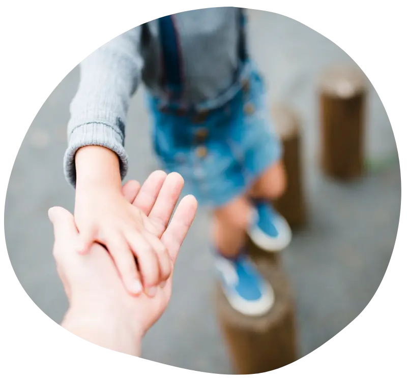 Ouder reikt hand uit naar kind dat balanceert – symbool voor steun, vertrouwen en samen groeien in opvoeding.