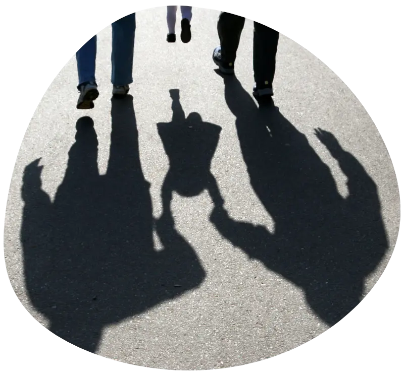 Schaduwen van ouders en kind hand in hand – symboliek voor begeleiding, verbondenheid en ruimte om te groeien.